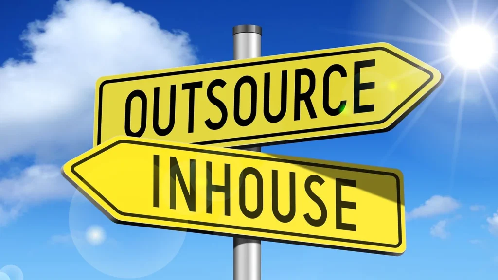 Roadsigns depicting choosing a direction between "inhouse" and "outsource"